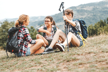 Mother hiking with her daughters.They taking a break and resting after long walk.	