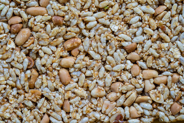 Granola bar. Healthy sweet dessert snack. Peanuts and rice with honey in background, close up