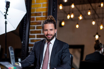 Portrait of beautiful man’s model, with long curls hair. Happy young businessman, dress in jacket, shirt and tie, have a photo shooting.