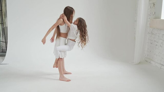 little girls with long hair in white clothes play, indulge, do acrobatic tricks