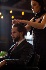 Close up of beautiful man’s long straight hair. Hairstylist combing and drying hair to handsome young businessman in a beauty salon.