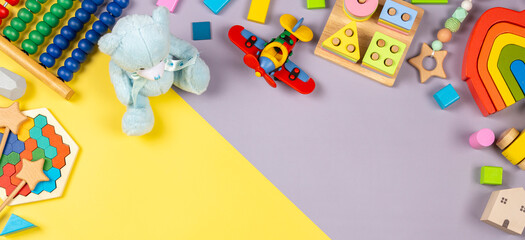 Baby kids toys frame. Colorful educational wooden plastic and fluffy toys for children on yellow and grey background. Top view, flat lay