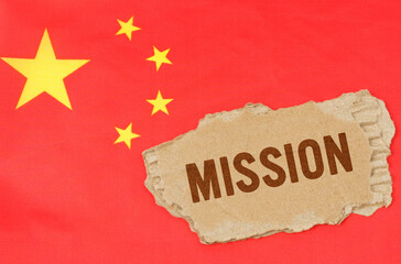 Against the background of the Chinese flag lies cardboard with the inscription -mission