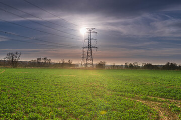 Linia elektryczna wysokiego napięcia oświetlona promieniami słonecznymi. © boguslavus
