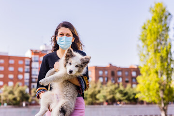 Beautiful dog, border collie puppy hugging with woman wearing a mask for covid-19. Lifestyle pet outside friendship