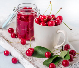 Cherry jam with fresh cherries on a blue background.