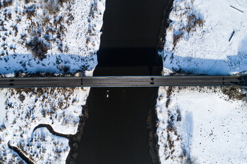 Topdwon aerial shot at winter river with a bridge over it
