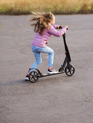 Little girl riding a scotter outdoor. Concept of healthy life.
