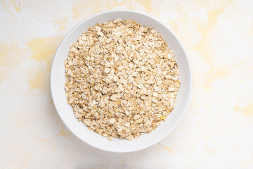 Oat flakes in a white plate on a yellow cement background