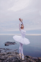 Fototapeta na wymiar Ballerina girl in ballet dress dancing by the lake