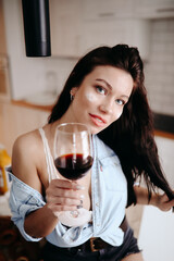 Beautiful brunette girl smiles and raises a glass of wine in a toast