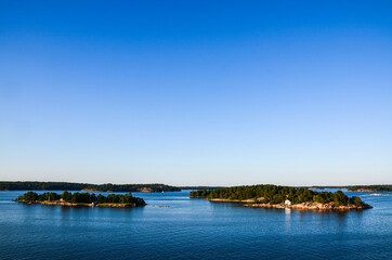 Rocky islands of Stockholm archipelago in Baltic sea with picturesque vacation houses and boats at sunset evening. Scandinavian landscape 