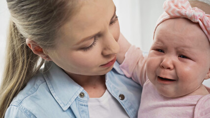 mother holding crying baby girl in arms.