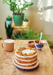 Banana cake with caramel. Wooden background, side view. In the background are home plants.