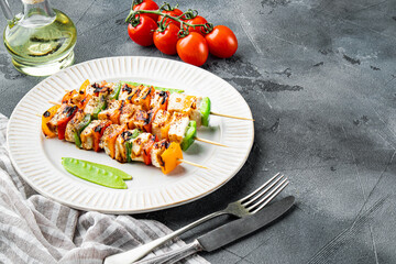 Grilled Malay chicken kebabs on a white plate on a gray background. Copyspace.