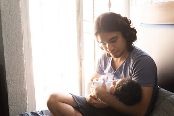 young happy hispanic father hugging and holding his newborn baby