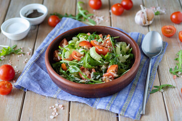 Vegetarian breakfast: Salad with arugula, tomatoes and celery on a brown plate on a wooden table