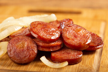 Sliced ​​calabrese sausage with onion on wooden background.