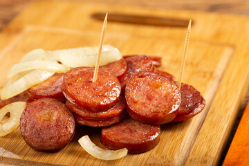 Sliced ​​calabrese sausage with onion on wooden background.