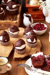 Chocolate cupcakes with cherries, cream and chocolate icing. Side view. Wooden background.