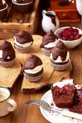 Chocolate cupcakes with cherries, cream and chocolate icing. Side view. Wooden background.