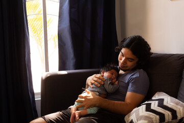 young happy hispanic father hugging and holding his newborn baby