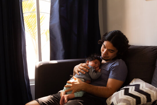 Young Happy Hispanic Father Hugging And Holding His Newborn Baby