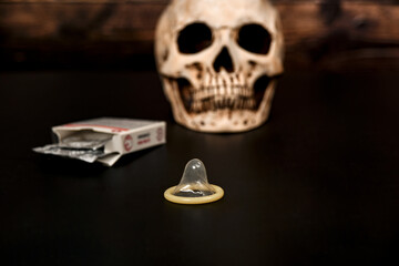 An open condom lies on the background of a human skull.
