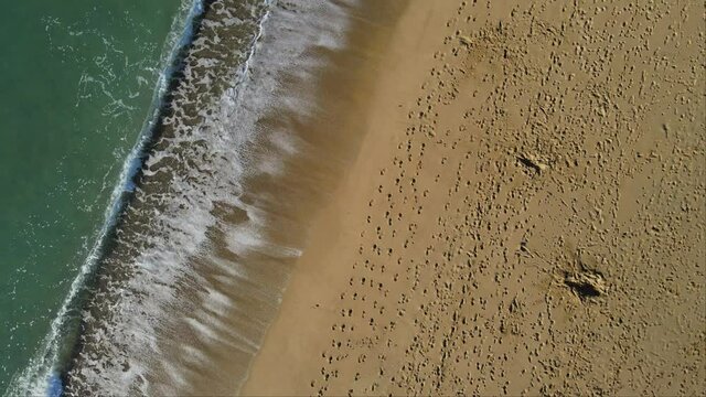 Aerial drone shot of footsteps and waves on the beach of Castell, Palamos, in the heart of the Costa Brava of Girona, Catalonia - Tomas a&eacute;reas con drone de pisadas y olas en la Playa del Castell