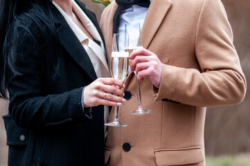 Glasses with white wine in the hands of a guy and a girl