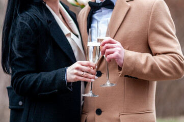 Glasses with white wine in the hands of a guy and a girl