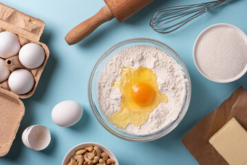 Baking ingredients flour, eggs, butter with rolling pin on a bright background.