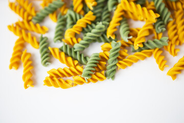 Fusilli pasta yellow and green on a white plate. Natural durum wheat pasta with pumpkin and spinach.