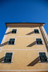 Fototapeta na wymiar Fragments of Italian streets. The yellow facade of the building with green shutters on the windows.