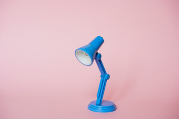 Mini desk lamp  blue color on bright pink background. Space for text. Concept: education, training, session, courses.