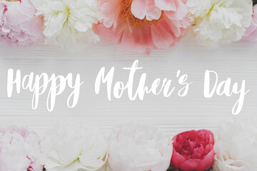 Happy mother's day. Happy mother's day text and  tender peony floral border on white wood flat lay....