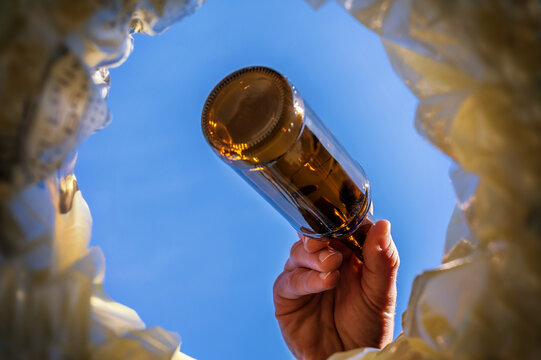 Glasflasche wird in M&uuml;lleimer getan mit Blick aus dem M&uuml;lleimer