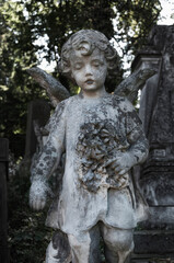 Little stone angel with a bouquet in his hands (concept of death, loss)