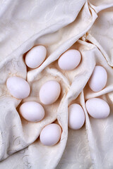 Chicken eggs on a white ornamented textile cloth.