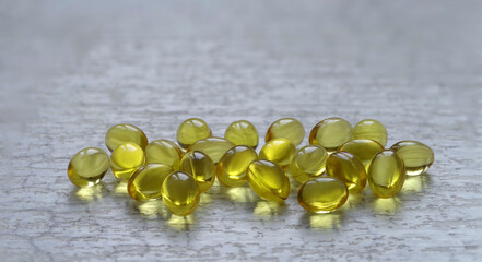 Yellow transparent oval capsules with a medicine. On a gray background.