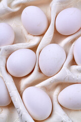 Close-up white eggs on a wrinkled curtain.