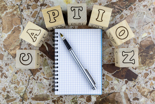 Caption concept with notebook and pen below arched alphabet letters on wooden cubes on a marbled stone background with copyspace. Flat lay