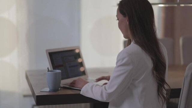 Frau arbeitet am Laptop und trinkt Kaffee