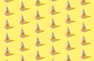 Creative birthday pattern made of birthday hats on yellow background. Minimal party concept.