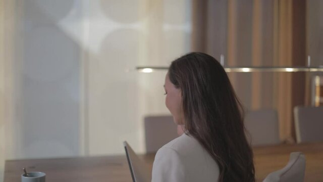 Frau telefoniert und geht an einen Tisch zum Arbeiten