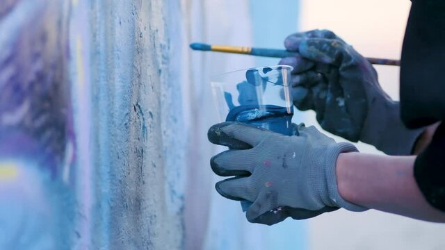 Artist paints blue paint wall