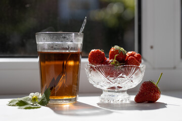 Cup of tea and wild strawberries on a white background