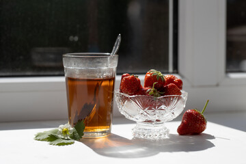 Cup of tea and wild strawberries on a white background