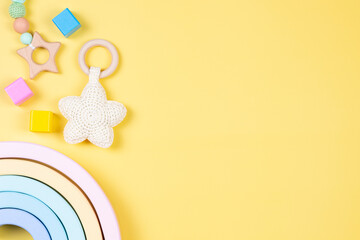 Baby kid toys on yellow background. Sustainable early childhood development baby stuff and natural pastel color wooden toys. Top view, flat lay.