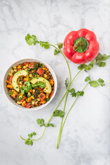 Slow cooker quinoa, sweet potato, and corn casserole with a sprig of cilantro and a red pepper.